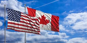 American and Canadian flags against a blue sky background